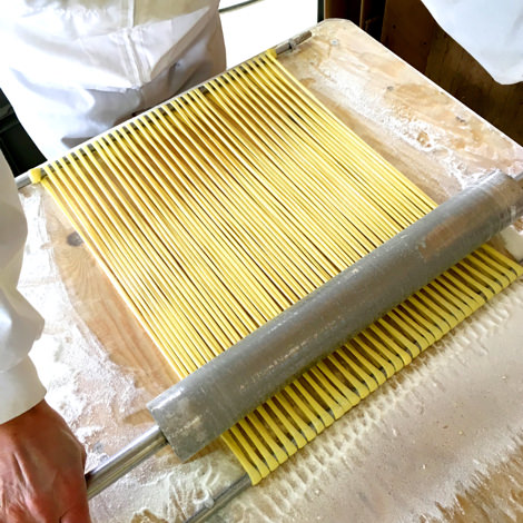 林泉堂の職人が稲庭ラーメンの麺線を麺棒で一本一本延ばす手延べ工程。機械製麺では再現できない手作業
